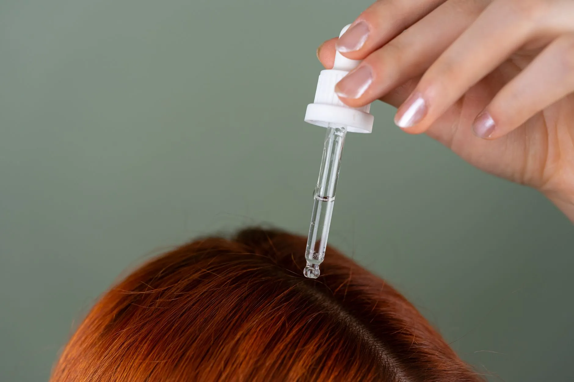 Conta-gotas aplicando loção na raiz do cabelo, direto no couro cabeludo